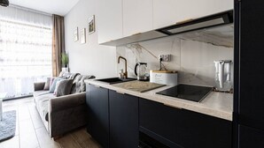 A modern kitchen with a black countertop, white cabinets, and a built-in stove. - Sereno Apartament Blisko pla y Widok na Natur (Trzebiatow)