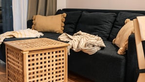 Ein dunkelbraunes Sofa mit vielen Kissen, einem gewebten Korb und einer gestreiften Decke.