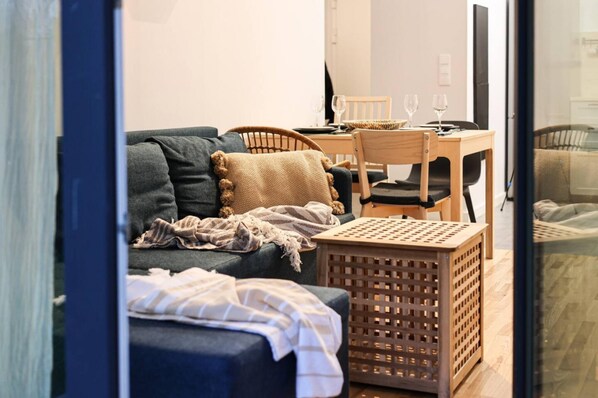En hyggelig opholdsstue med en mørkeblå sofa, et træsofabord og en lille træskammel.