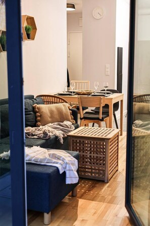 En hyggelig opholdsstue med sofa, spisebord dækket til to og en fletkurv.