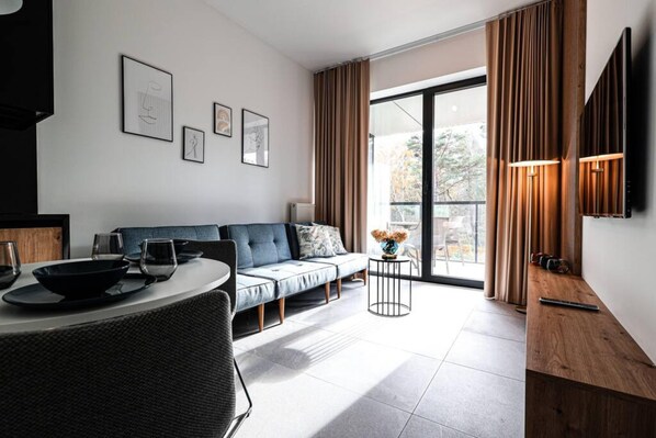 A modern living room with a sofa, dining table, and artwork on the wall.