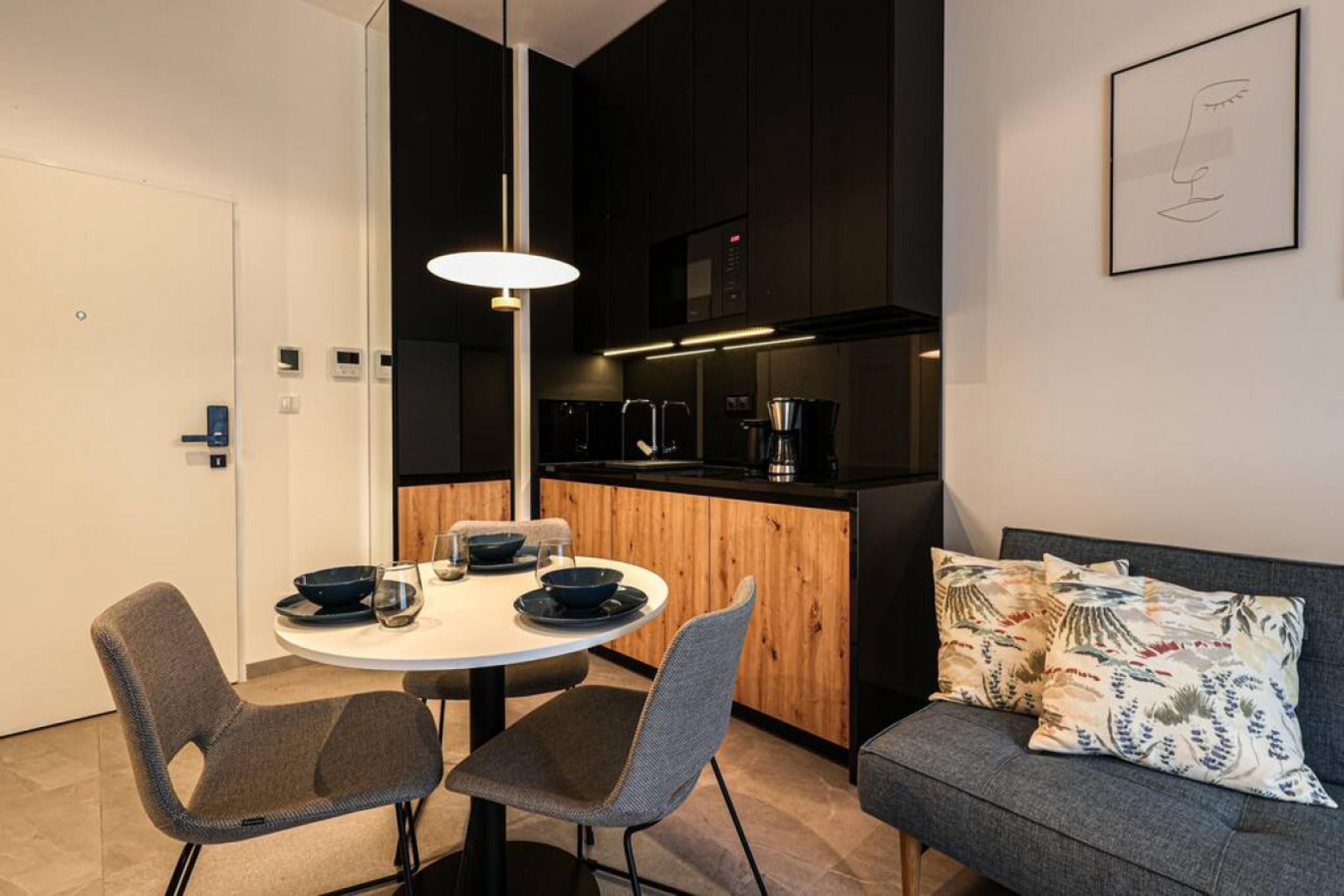 Una cocina moderna con comedor, que incluye una mesa redonda con sillas, un sofá y una cafetera.