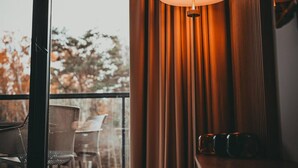 Een kamer met een groot raam, een tafel met stoelen en een lamp.