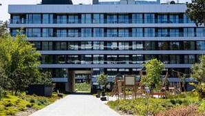 A modern multi-story building with a central entrance, surrounded by greenery and outdoor play structures. - Art Forrest 33 M in Rogowo (Trzebiatow)
