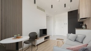 A modern living room with a flat-screen TV, a dining table, and a sofa. - Art Forrest 33 K in Rogowo (Trzebiatow)