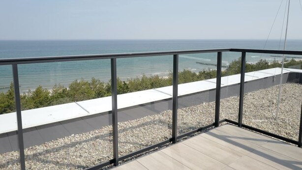 A balcony with a clear view of the sea and a rocky shoreline. - Art Forrest 33 K in Rogowo (Trzebiatow)