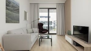 A modern living room with a sofa, a chair, a coffee table, a TV, and a large window with curtains. - Art Forrest 33 B in Rogowo (Trzebiatow)
