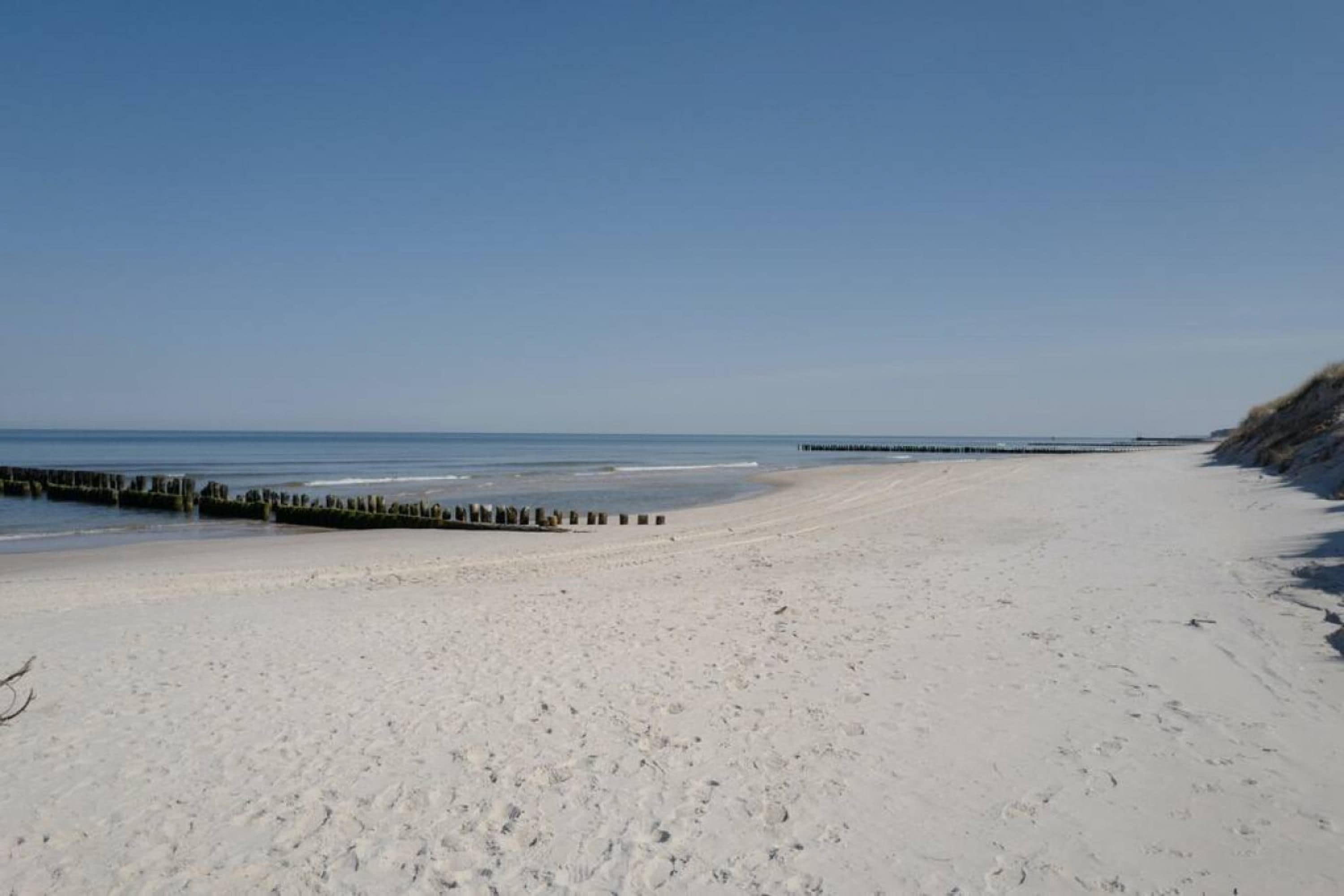 A wide sandy beach with a clear sky and calm sea.