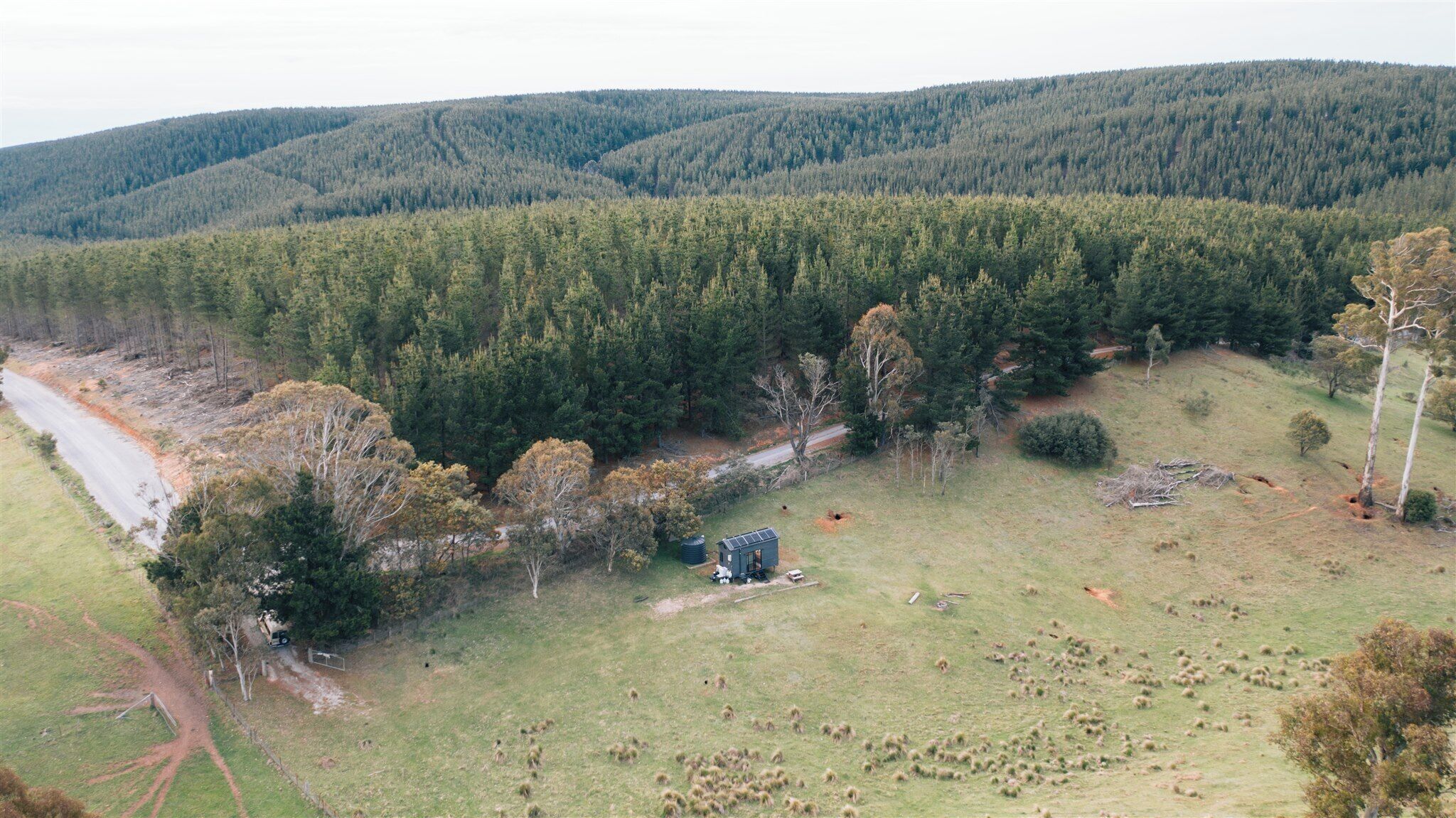 A remote cabin in a forested area with a clear view of the surrounding hills.