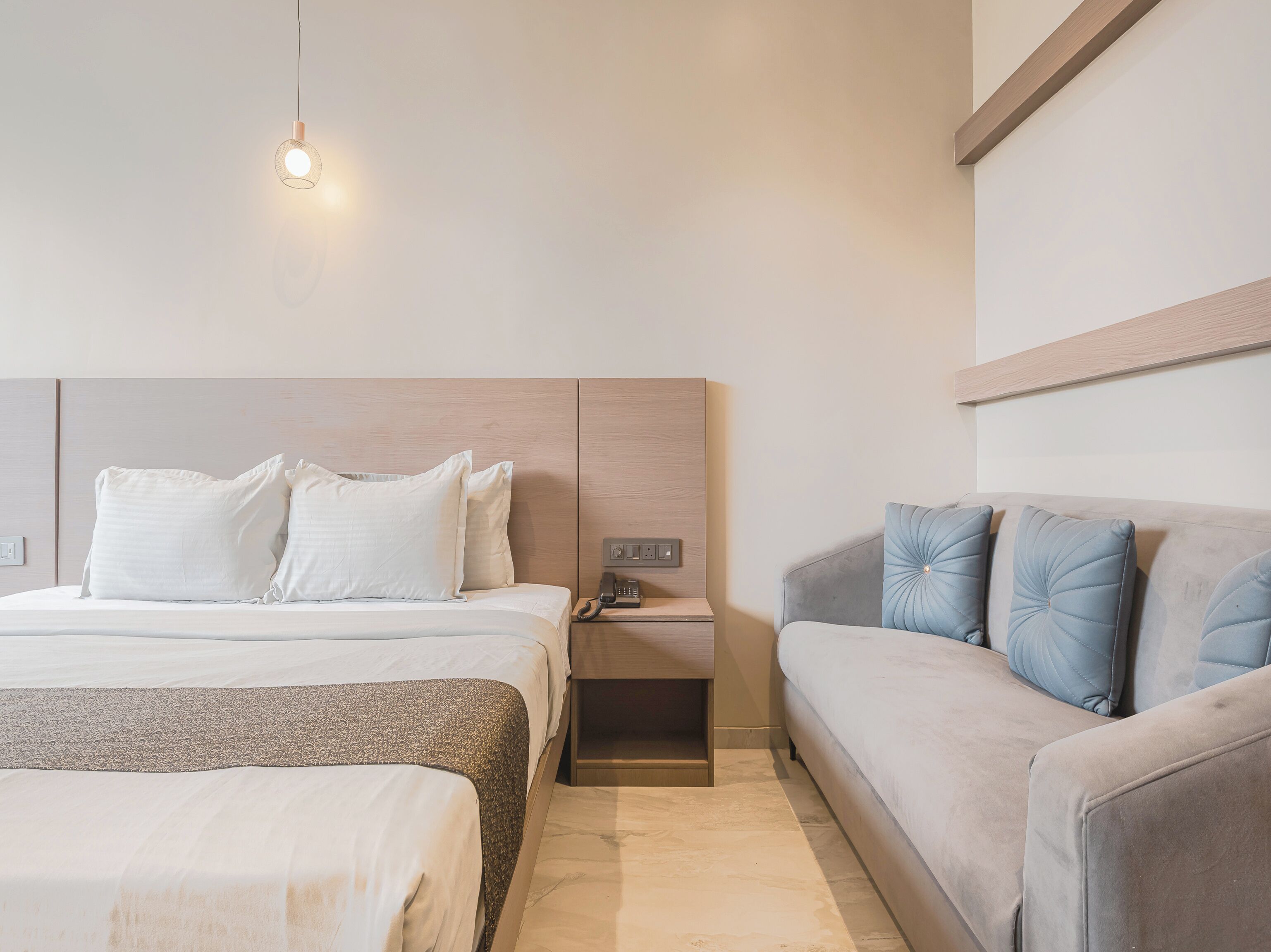 Una habitación de hotel con una cama, una mesita de noche, un teléfono y un sofá.