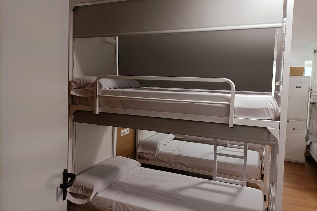 A bunk bed room with three levels, each with a mattress and pillows.