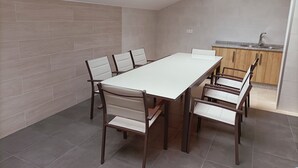 A modern kitchen with a skylight, a dining area with a long table and chairs, and a kitchen counter with a sink. - ALBERGUE VALIN LAMA (Palas de Rei)