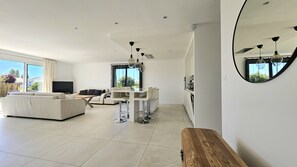 A modern living room with a sofa, a dining table with chairs, a TV, and a large window with curtains. - Belle Maison 4 ch- 8pers. Mornac (Mornac-sur-Seudre)