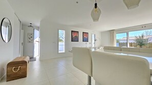 A spacious living room with a large window, a sofa, and a wooden chest of drawers. - Belle Maison 4 ch- 8pers. Mornac (Mornac-sur-Seudre)