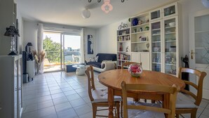 En rummelig opholdsstue med spisebord, stole, sofa og bogreol.