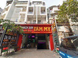 A building with a prominent red and yellow sign for 'TAM MY' hotel, featuring a neon sign and a motorcycle parked in front. - Tam My Hotel (Ho Chi Minh City)