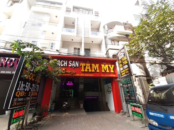 A hotel entrance with a red awning and neon signs advertising room rates. - Tam My Hotel (Ho Chi Minh City)