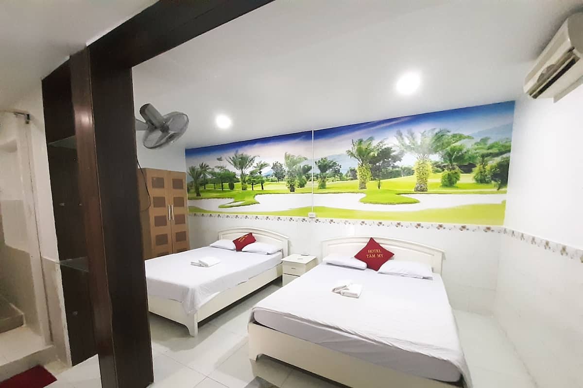A hotel room with two single beds, a mural of a golf course, a ceiling fan, and an air conditioning unit.