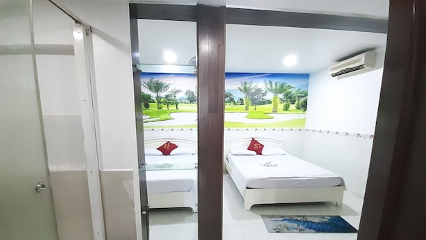 A hotel room with two beds, a view of a golf course, and a red mat at the entrance. - Tam My Hotel (Ho Chi Minh City)