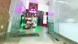 A hotel entrance with a neon sign, a Coca-Cola refrigerator, and a reception desk. - Tam My Hotel (Ho Chi Minh City)