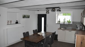 Une cuisine moderne avec des meubles blancs, une table à manger en bois et une fenêtre agrémentée de plantes.