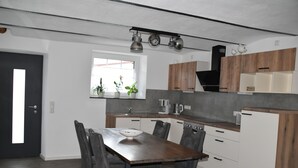 Une cuisine moderne avec une table à manger en bois, des chaises grises et des placards intégrés.