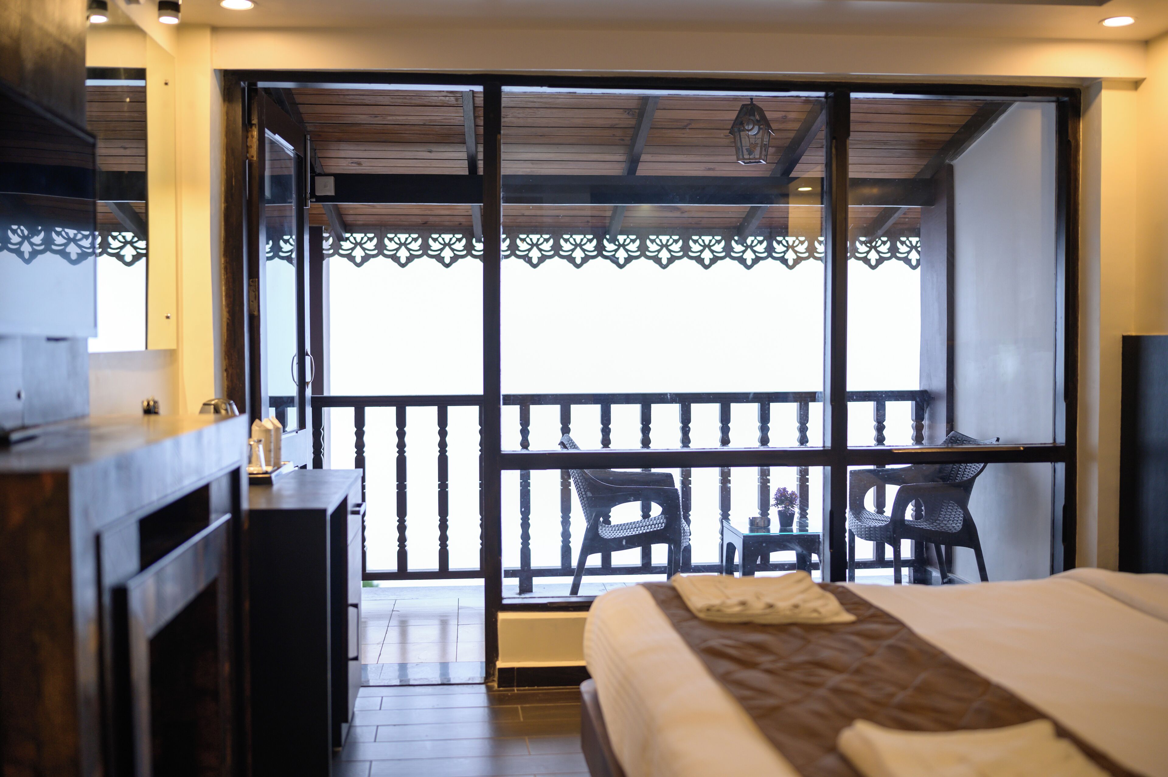 Een hotelkamer met een bed, een bureau en een balkon met stoelen.