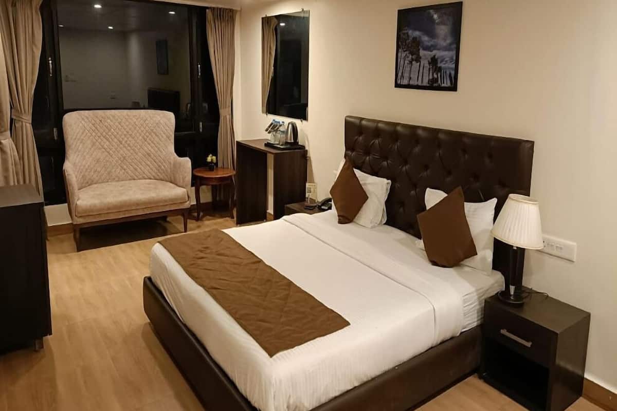 A hotel room with a large bed, a chair, a bedside table, and a nightstand.