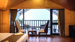 Une pièce en bois avec un balcon, deux chaises, une table et un lit.