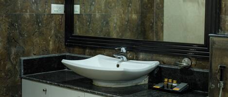 Un baño con un lavamanos blanco, encimera negra y un espejo grande.