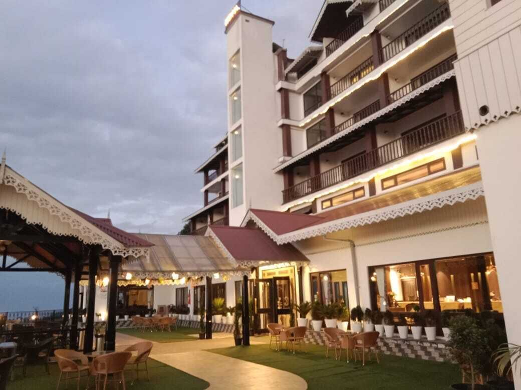 A hotel with multiple balconies, outdoor seating, and a well-lit entrance.