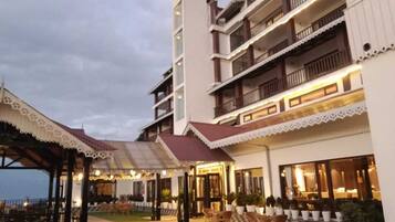 A hotel with multiple balconies, outdoor seating, and a well-lit entrance.