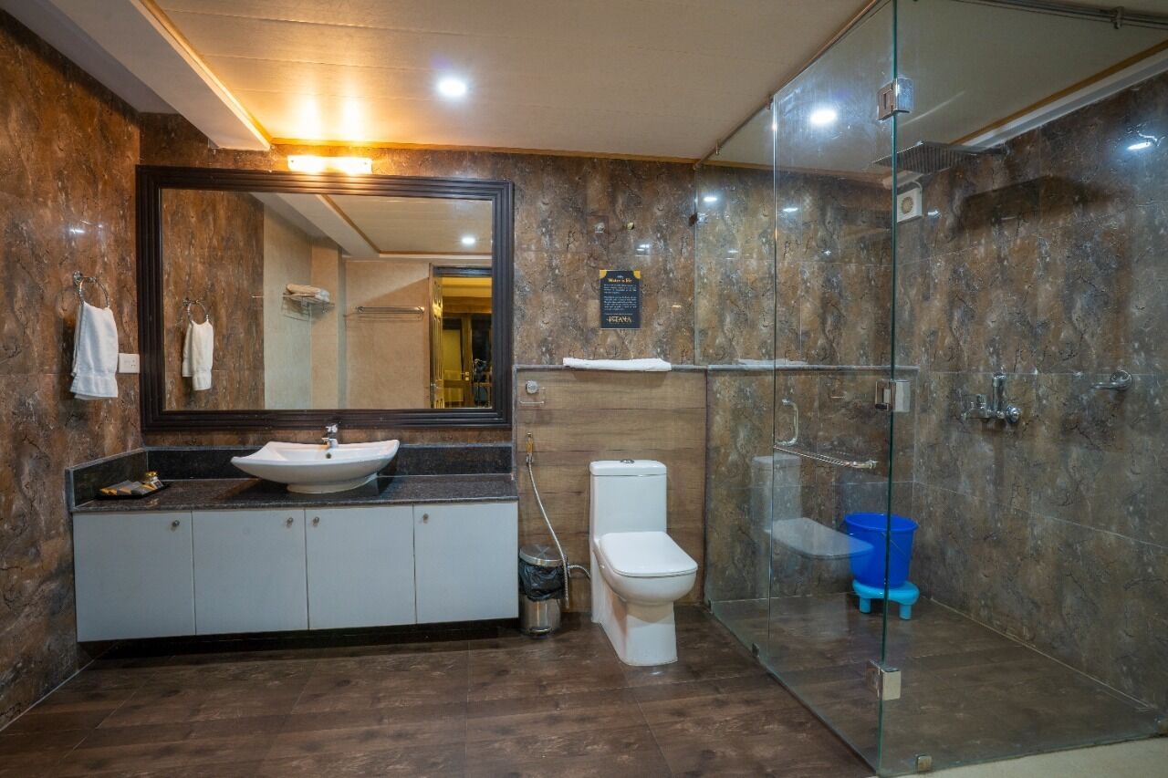 A modern bathroom with a large mirror, a sink, a toilet, and a glass-enclosed shower area.