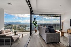 Un salon moderne avec une grande fenêtre, un canapé, une table basse et une plante en pot.