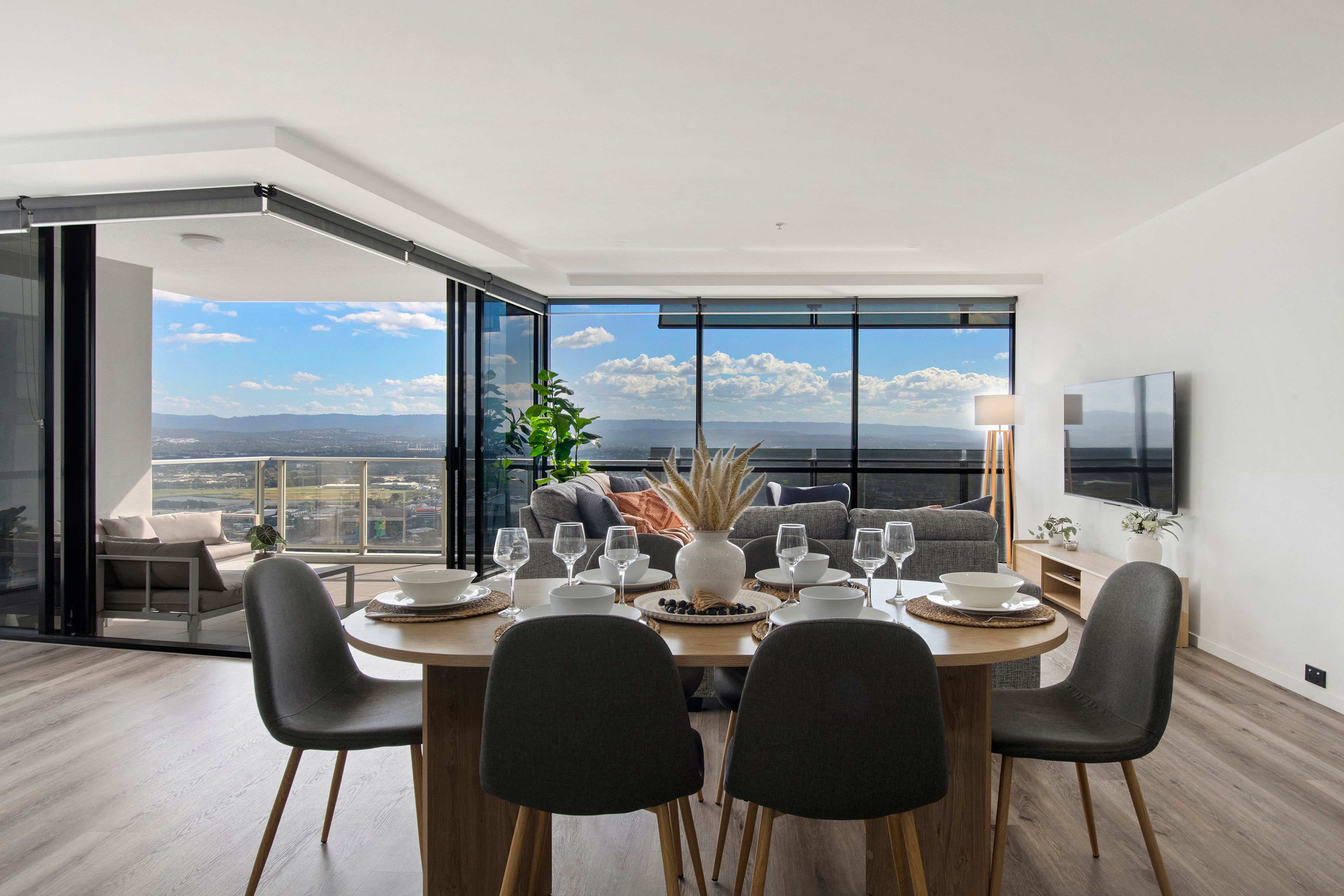 A modern dining area with a panoramic view, a flat-screen TV, and a cozy seating arrangement.