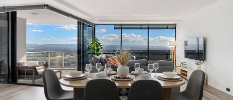 Un comedor moderno con vistas panorámicas, un televisor de pantalla plana y una zona de estar acogedora.