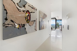 Un couloir orné d’œuvres d’art abstrait, qui mène à une pièce offrant une vue panoramique.