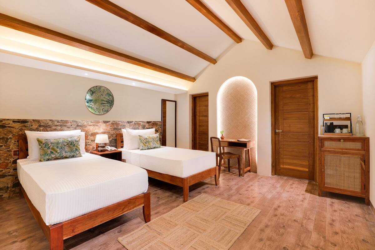 A bedroom with two beds, a desk, a chair, and a cabinet.