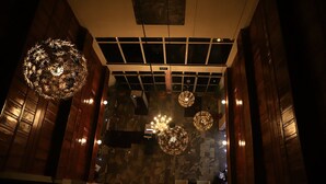 A lobby with wooden paneling, a glass partition, and three ornate chandeliers. - Signatious Hotel and Suites (Warri)