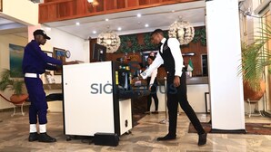 A reception area with a reception desk, a clock, and a decorative wall. - Signatious Hotel and Suites (Warri)