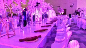 A banquet hall with long tables set for a formal event, decorated with floral arrangements and white tablecloths. - Signatious Hotel and Suites (Warri)