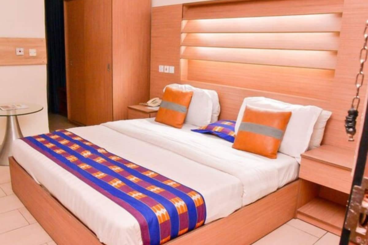 A hotel room with a wooden bed, a bedside table with a phone, and a small round table.