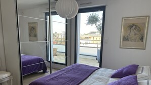 Ein Schlafzimmer mit einem Bett, einem großen Spiegel und Blick ins Freie.