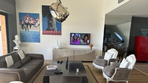 Ein modernes Wohnzimmer mit einer Couch, Sesseln, einem Couchtisch und Kunstwerken an den Wänden.
