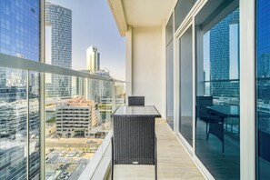 Enjoy the city view from this balcony with a glass railing and a small table.