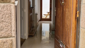 Un couloir avec une porte en bois, un radiateur blanc et un sol carrelé.
