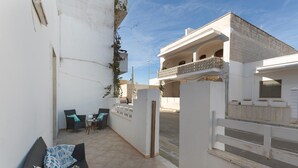 A courtyard with a seating area, a white wall, and a building with a balcony. - 3681 Casakore by Barbarhouse (Porto Cesareo)