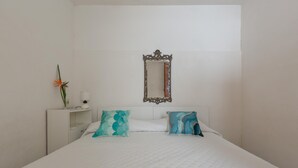 A bedroom with a large bed, two pillows, a nightstand with a vase and a lamp, and a mirror on the wall. - 3681 Casakore by Barbarhouse (Porto Cesareo)