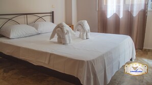 A neatly made bed with white linens and two towels placed on it. - Family Central in Kalamata (Kalamata)
