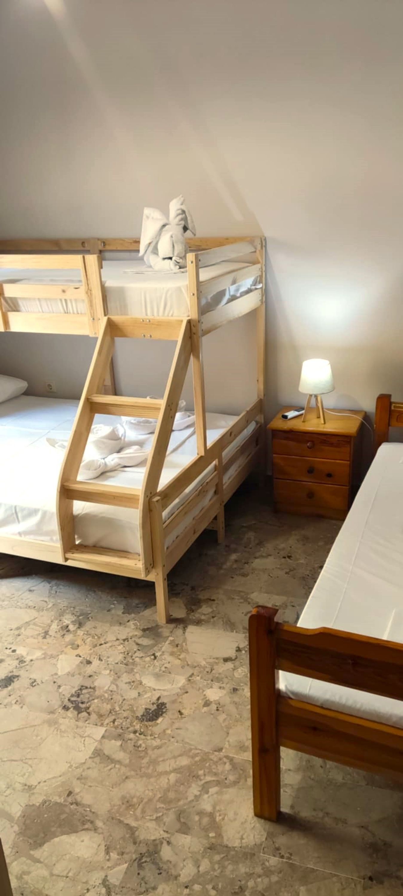 A bunk bed with a ladder, a bedside table with a lamp, and a wooden chair.